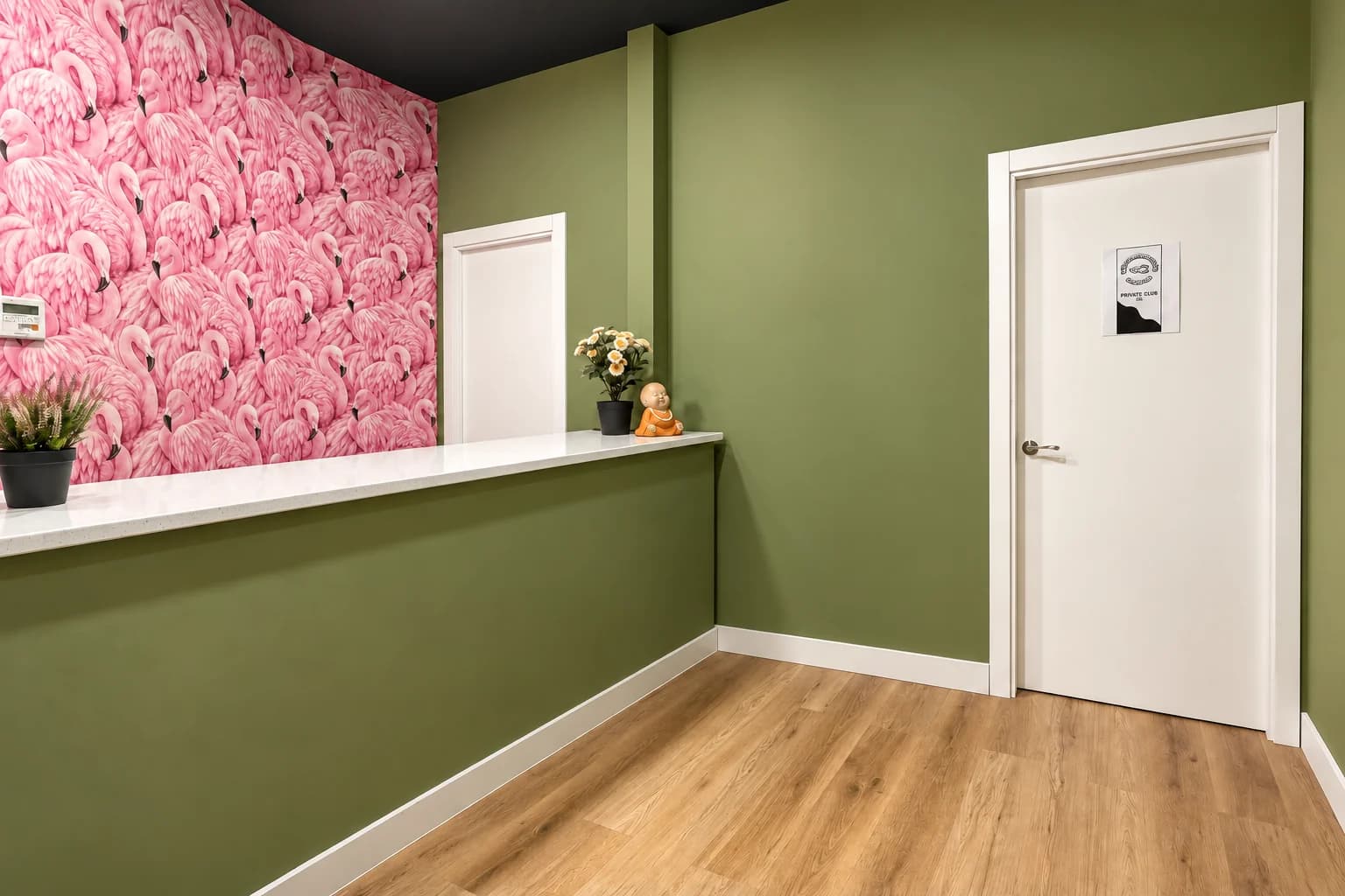Weed Club Chueca reception with a white countertop and a wall decorated with pink flamingos